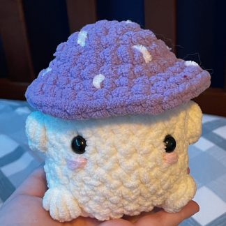 A short crocheted purple mushroom with a face.