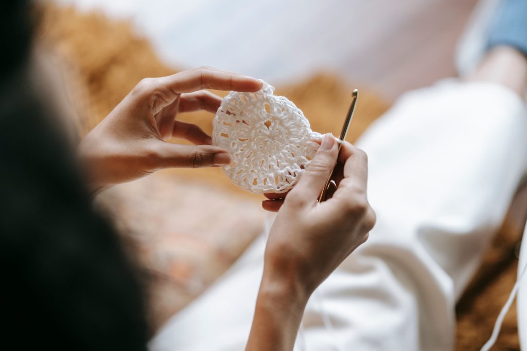 A person crocheting aa circle with white yarn.
